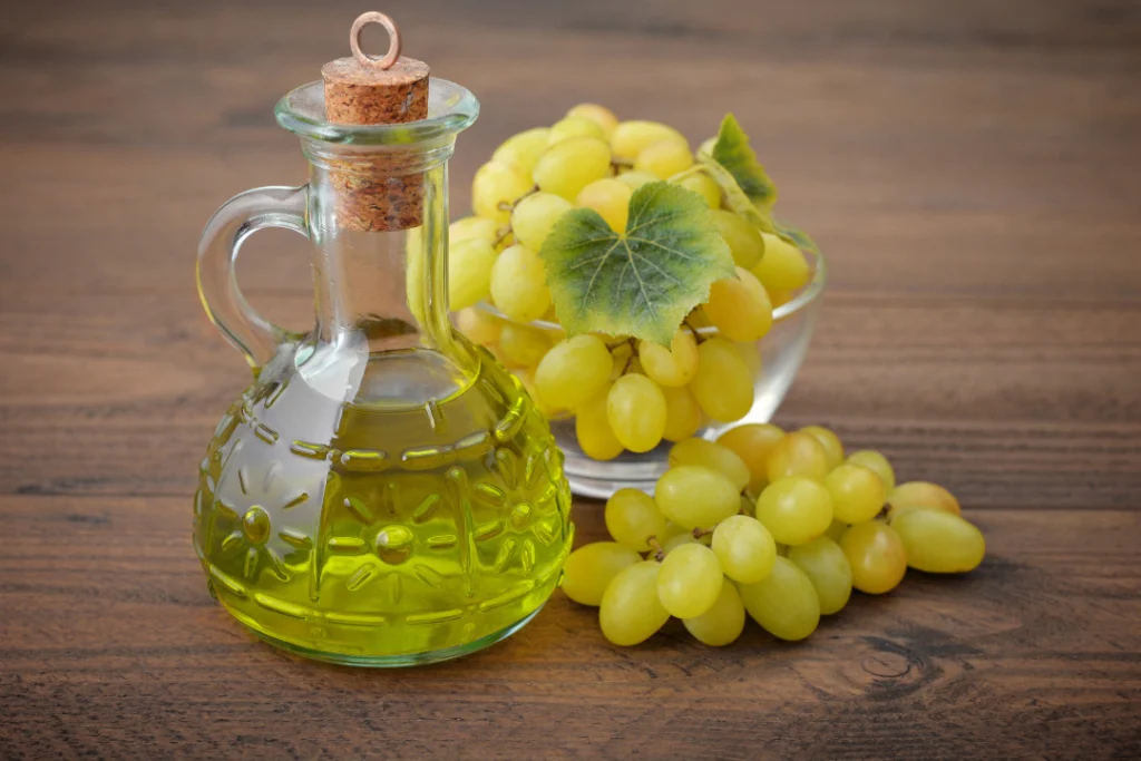 grape seed oil in a glass jar and grapes on the wooden table